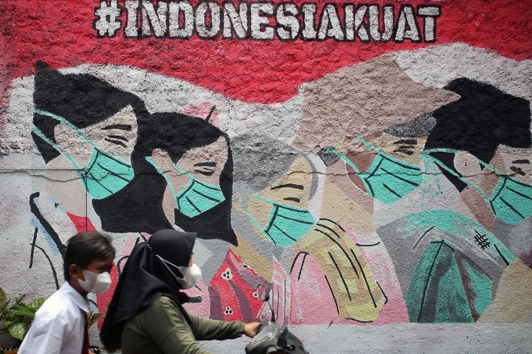 Pengendara motor melintas di depan mural yang bergambar ajakan menggunakan masker yang ada di kawasan Cireunde, Tangerang Selatan, Banten, Selasa (15/2/2022). Tingginya angka penyebaran dan penularan COVID-19 di Tangsel membuat sejumlah warga mengajak warga yang lain tetap patuh terus menggunakan masker di tengah mulai memudarnya ketaatan penggunaan masker demi meminimalisir penyebaran COVID-19. ANTARA FOTO/Muhammad Iqbal/foc.