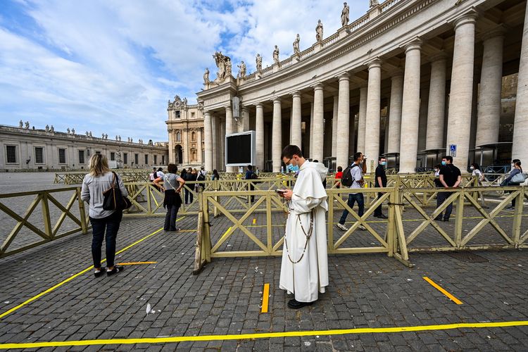 Warga maupun rohaniwan berbaris rapi mengikuti aturan pembatasan sosial untuk memasuki Basilika Santo Petrus di Vatikan pada 18 Mei 2020. Basilika tersebut ditutup lebih dari dua bulan untuk mencegah penyebaran virus corona.