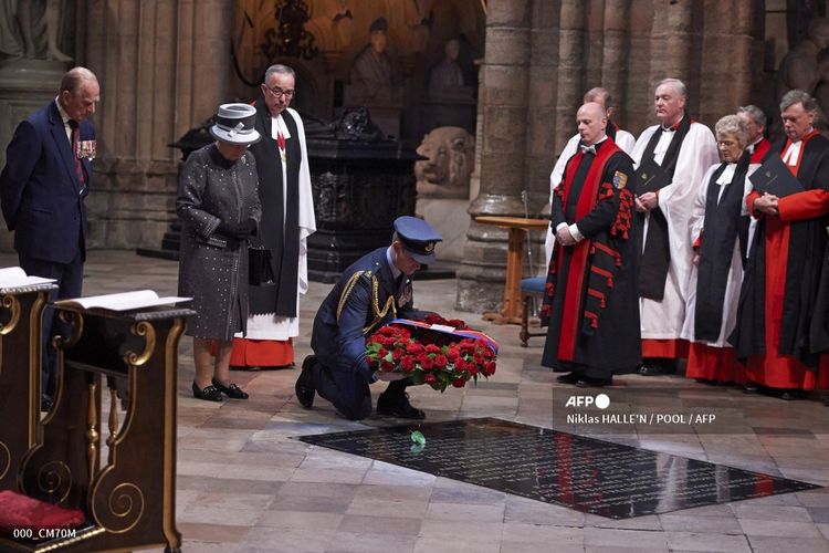 Seorang anggota militer meletakkan karangan bunga yang terbuat dari mawar dan daun salam di Makam Prajurit Tak Dikenal atas nama Ratu Inggris Elizabeth II (kedua dari kiri) pada Kebaktian pada Malam Seratus Tahun Pertempuran Somme di Westminster Abbey di London pada 30 Juni 2016. 