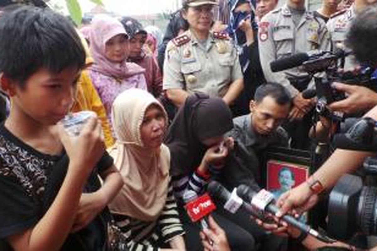 Keluarga almarhum Aiptu Dwiyatna, istri korban, Warsih (tengah, berjilbab krem), beserta anak-anaknya saat memberikan keterangan kepada wartawan seusai memakamkan Aiptu Dwiyatna, di tanah wakaf, Pamulang Barat, Tangerang Selatan, Rabu (7/8/2013).