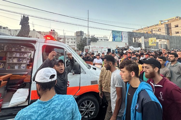 Orang-orang berkumpul di sekitar ambulans yang rusak akibat serangan Israel di depan rumah sakit Al-Shifa di Kota Gaza pada tanggal 3 November 2023, ketika pertempuran antara Israel dan gerakan Hamas Palestina terus berlanjut. Menurut kepala layanan pers pemerintah Hamas, serangan tersebut menargetkan konvoi ambulans yang sedang bersiap untuk mengangkut orang-orang yang terluka dari rumah sakit Al-Shifa ke perbatasan dengan Mesir. Beberapa orang tewas dan terluka dalam serangan tersebut. 