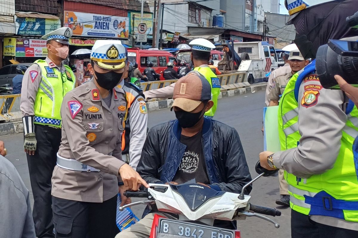 Kasat Lantas Polres Metro Jakarta Selatan Kompol Yunita Rungkat saat mengecek surat-surat berkendara seorang pengendara motor yang tak menggunakan helm di persimpangan Pasar Minggu, Jakarta Selatan, Rabu (6/3/2024).