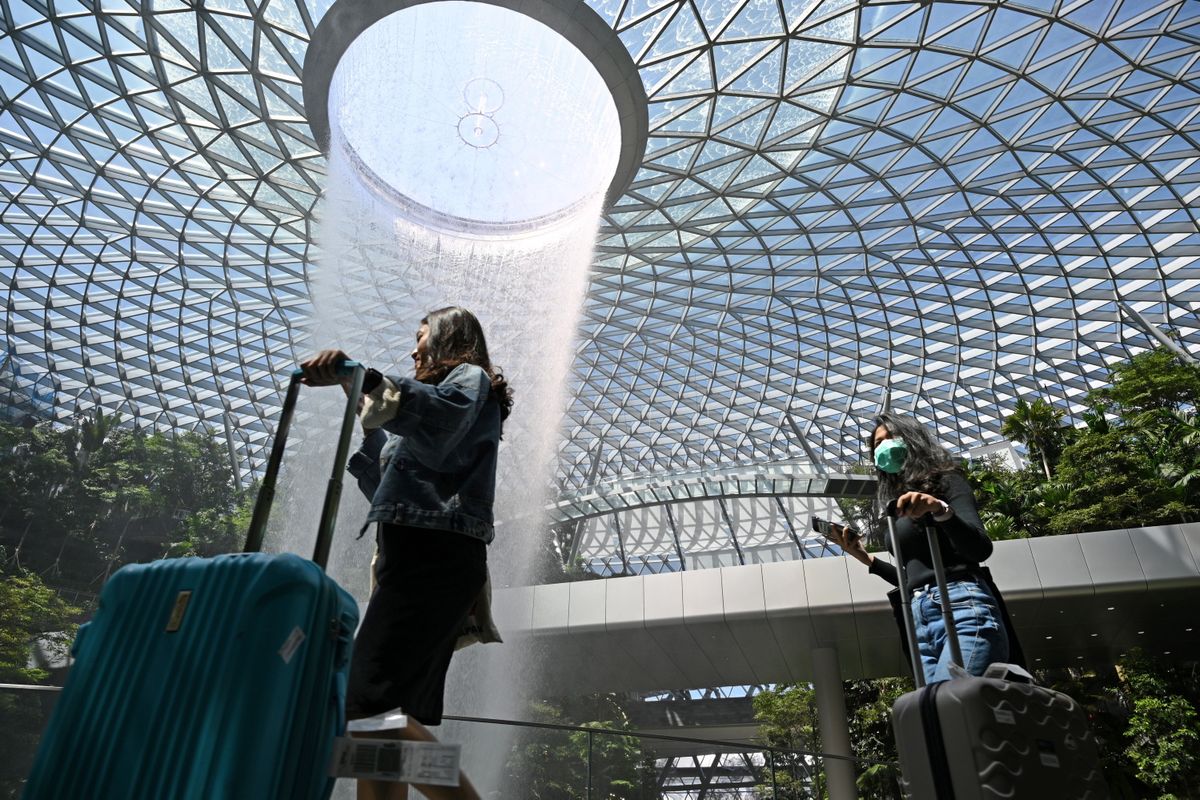 Seorang penumpang (kanan) mengenakan masker saat melintas di Jewel Bandara Changi di Singapura, 27 Februari 2020, menyusul penyebaran Covid-19 novel coronavirus.