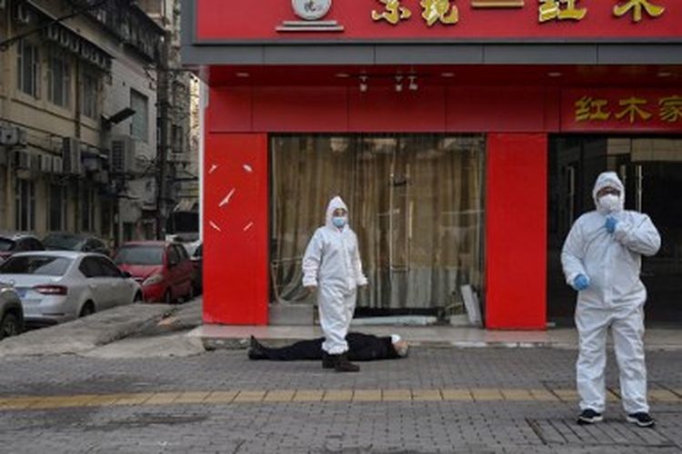 Foto yang diambil pada 30 Januari 2020 ini menunjukkan petugas berbaju pelindung memeriksa seorang lelaki tua yang meninggal di jalan Kota Wuhan di provinsi Hubei tengah Tiongkok, asal penyebaran Covid-19 ke berbagai penjuru dunia.