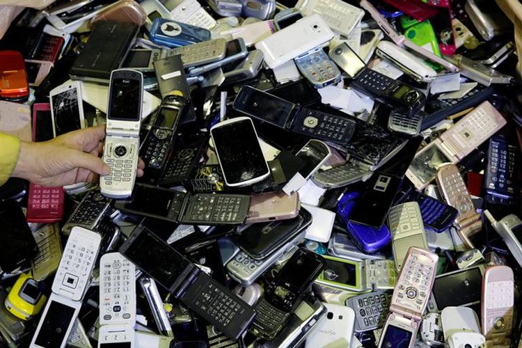 Seorang pekerja sedang memeriksa tumpukan ponsel bekas yang akan digunakan sebagai bahan pembuat medali untuk ajang Olimpiade dan Paralimpiade Tokyo 2020. Gambar diambil pusat fasilitas daur ulang di Tokyo, Selasa (4/7/2017).  