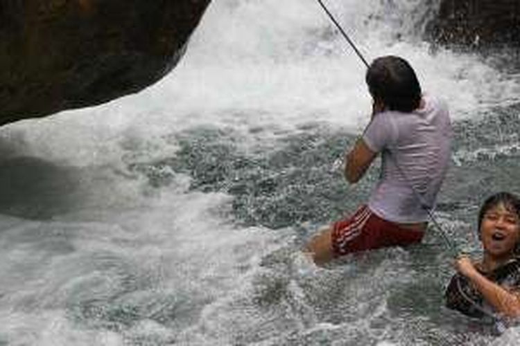 Dua pengunjung berpegang pada tambah yang telah disediakan warga untuk bertahan dari arus curug yang deras di Curug Ciburial, Desa Cibadak, Bogor, Jawa Barat.
 
