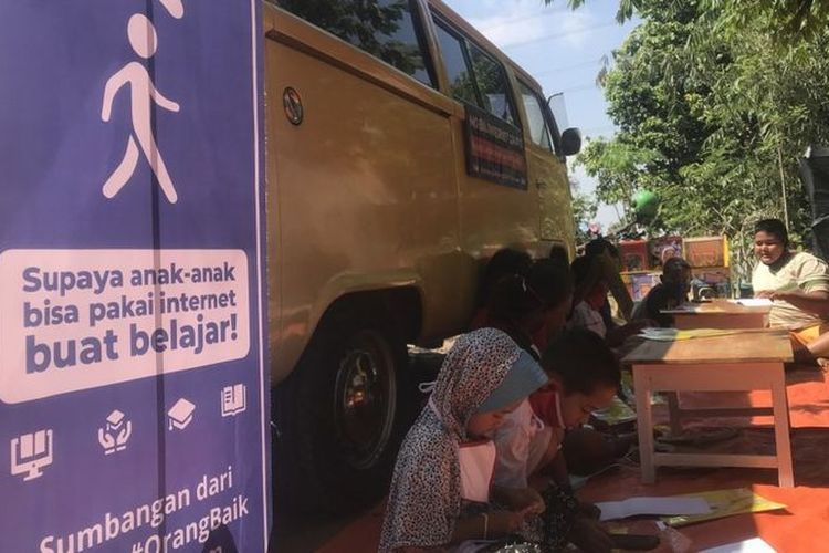 Anak-anak menggunakan layanan internet gratis untuk menyelesaikan tugas sekolah.