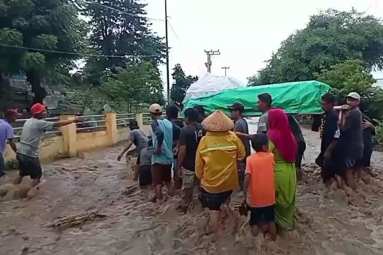 Tampak warga menggotong keranda jenazah dengan menerobos banjir di Desa Sandue, Kecamatan Sanggar, Kabupaten Bima, Kamis (4/4/2024).