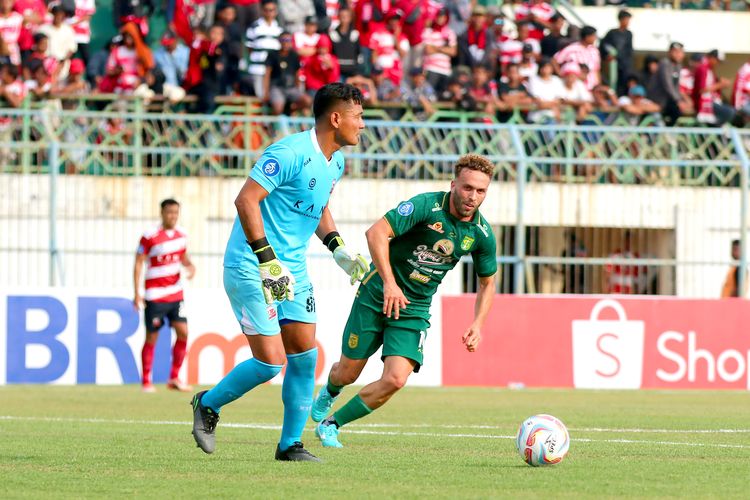 Penjaga gawang Madura United Wawan Hendrawan dan pemain Persebaya Surabaya Ze Valente mengejar bola saat pertandingan pekan ke-12 Liga 1 2023-2024 yang berakhir dengan skor 3-0 di Stadion Gelora Bangkalan, Minggu (17/9/2023) sore.