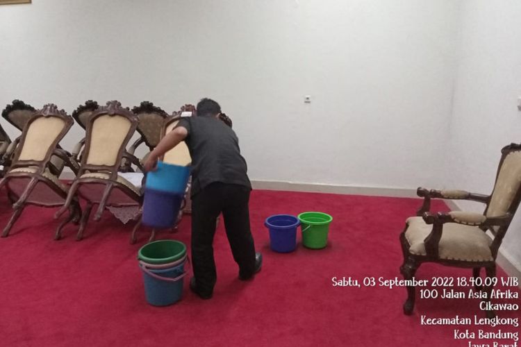 Petugas Gedung Merdeka saat menadah air hujan dengan ember.