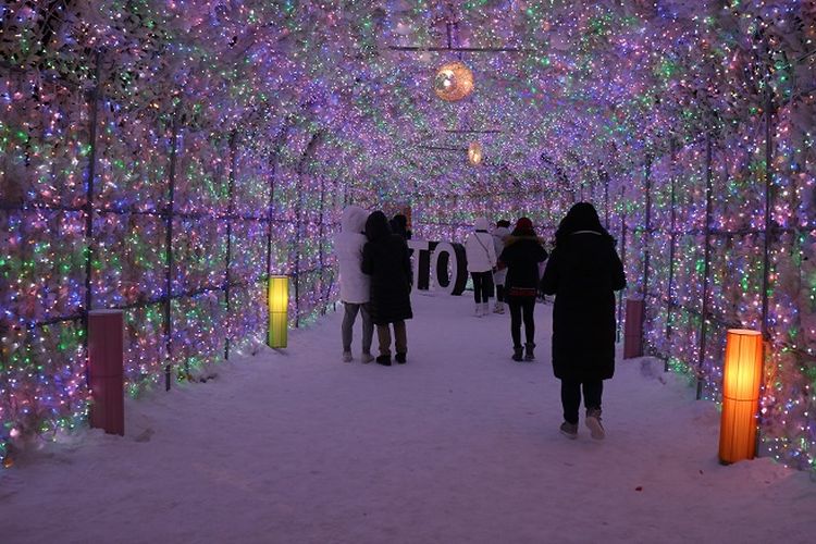 Wisatawan menikmati wisata buatan berupa terowongan yang dihias dengan lampu-lampu warna-warni di Kota Toyako, Prefektur Hokkaido, Jepang, Selasa (12/2/2019). Wisata buatan seperti lampu warna-warni bisa ditemukan saat musim salju di Hokkaido.