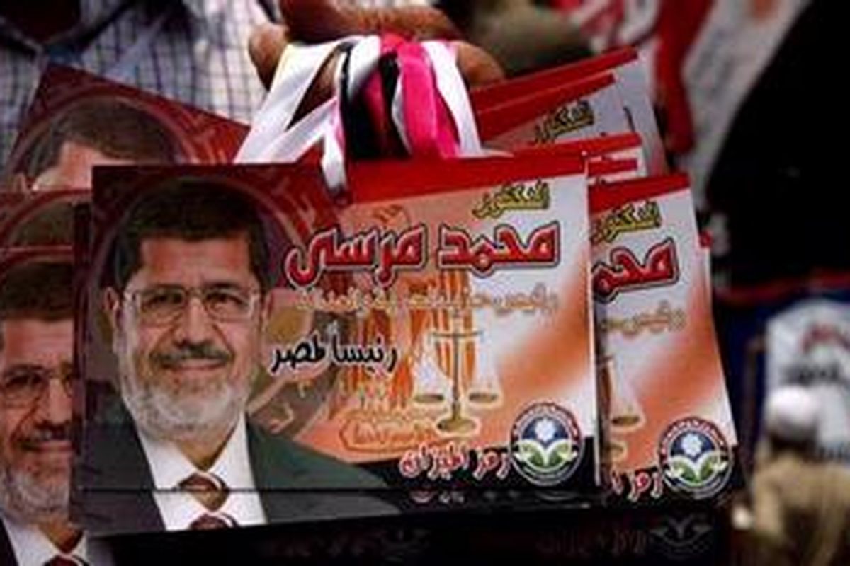 Pedagang menjual atribut bergambar foto calon presiden Mesir, Mohamed Mursi, dari Ikhwanul Muslimin. Mursi diumumkan sebagai pemenang Pilpres Mesir, Minggu (24/6/2012), dengan mengalahkan pesaingnya, Ahmad Shafiq.