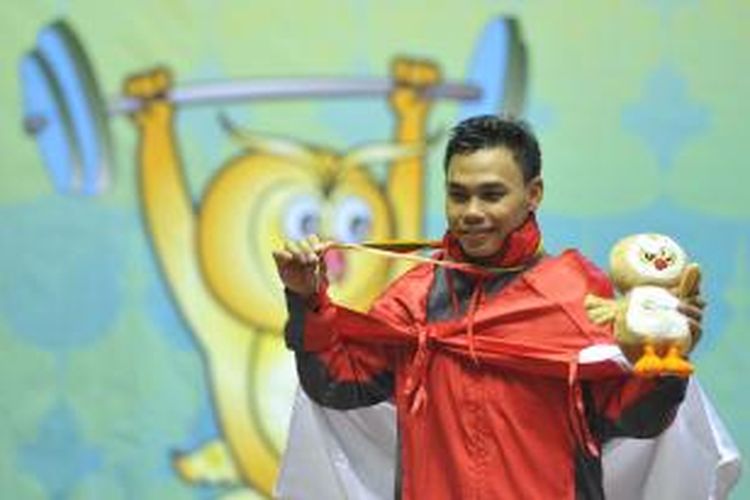 Lifter putra Indoensia, Eko Yuli Irawan memamerkan medali emas yang ia peroleh dalam laga angkat besi SEA Games 2013 kelas 62 kg di Stadion Theinphyu, Yangon, Myanmar, Jumat (13/12). Dengan total angkatan seberat 304 kg, Eko dinobatkan menjadi pria terkuat di kelas tersebut dan berhak dikalungi medali emas.