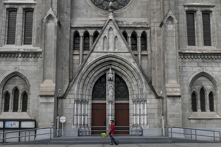 Petugas kebersihan melintas di depan pintu Gereja Katedral, Jakarta, Minggu (5/4/2020). Setelah Kemenkes resmi merilis Peraturan Menteri Kesehatan No.9 Tahun 2020 tentang Pembatasan Sosial Berskala besar (PSBB) dalam Rangka Perception Penanganan COVID-19, bentuk ibadah gereja dilakukan secara live streaming melalui media sosial, termasuk rangkaian ibadah paskah yang akan jatuh mulai Kamis (9/4/2020) hingga Minggu (12/4/2020).