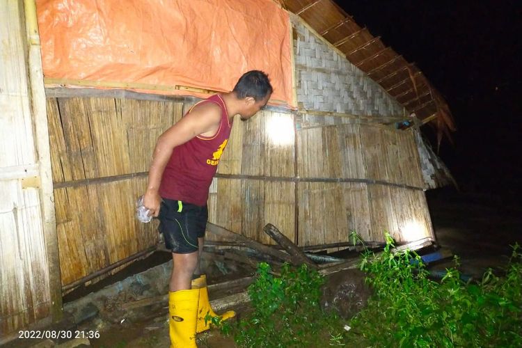 Seorang warga di Kabupaten Bone Bolango memeriksa bagian belakang rumah yang telah miring akibat luapan banjir. Sejumlah desa di 6 Kecamatan terendam banjir akibat curah hujan yang tinggi.