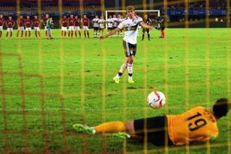 Penyerang Bayern Muenchen, Thomas Mueller, gagal mengeksekusi penalti setelah tembakannya ditepis kiper Guangzhou Evergrande, Zeng Cheng, pada laga persahabatan di Guangzhou, Kamis (23/7/2015). 