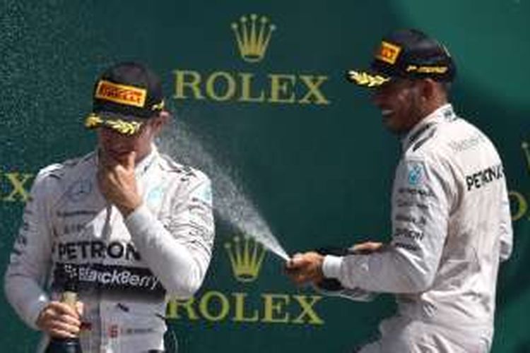 Pebalap Mercedes asal Inggris, Lewis Hamilton (kanan), dan rekan satu timnya asal Jerman, Nico Rosberg, merayakan di atas podium Sirkuit Siverstone setelah finis pertama dan kedua pada balapan GP Inggris, Minggu (5/7/2015).