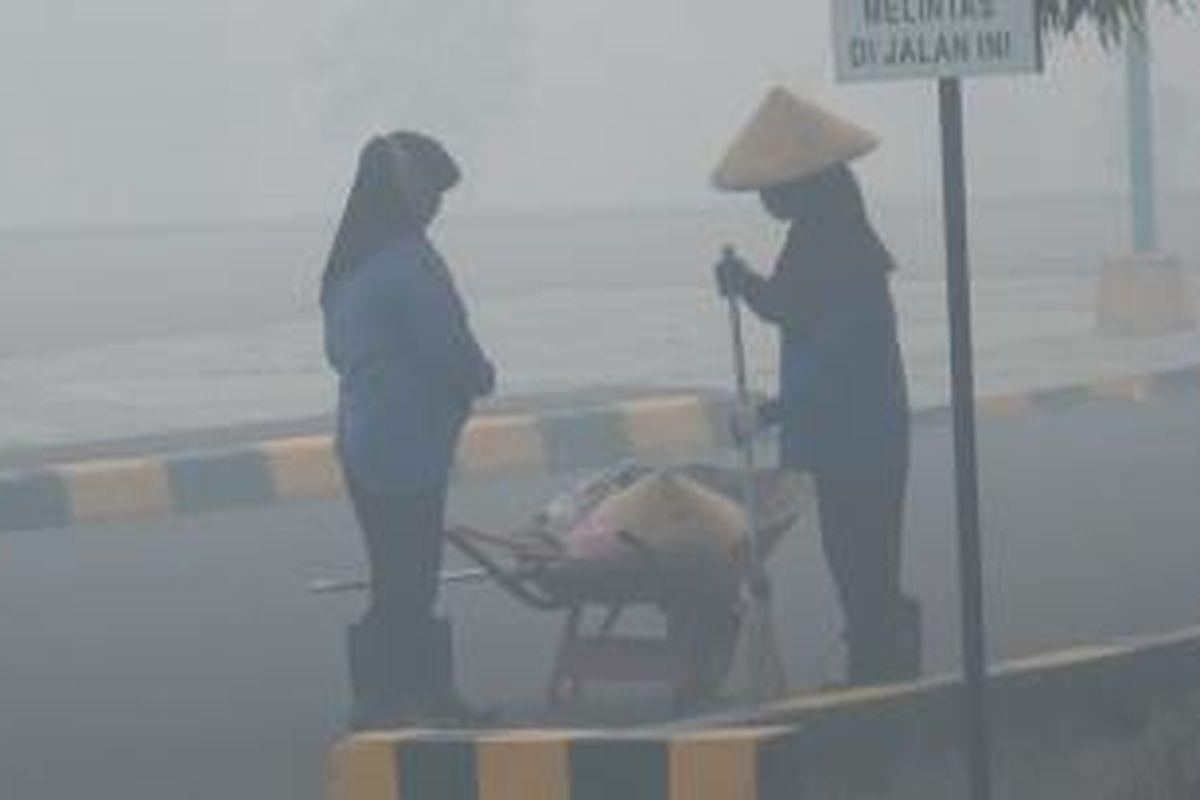 Tenaga kebersihan Universitas Sriwijaya Indralaya Ogan Ilir tetap bekerja di bawah kabut asap tebal, Sabtu (26/9/2015).