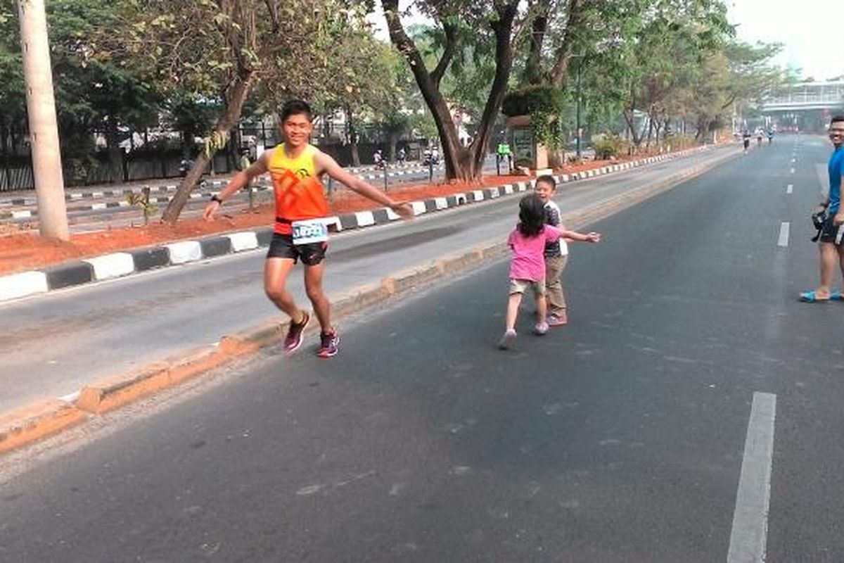 Seorang peserta lari Jakmarathon di Jalan Rasuna Said saat berpapasan denga warga yang sedang berolah raga, Minggu (25/10/2015).