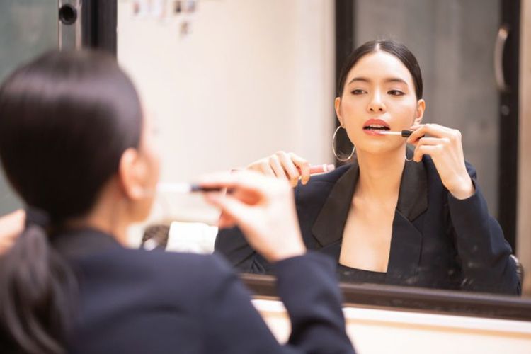 Ilustrasi wanita sedang merias bibir. 