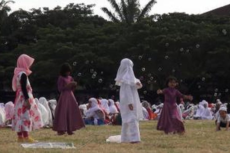 Sejumlah anak terlihat bremain balon gelembung sabun sambil menunggu orantua mereka usai melaksanakan Salat Idul Fitri 1435H di Lapangan Blang Padang Banda Aceh, Senin (27/8/2014).
