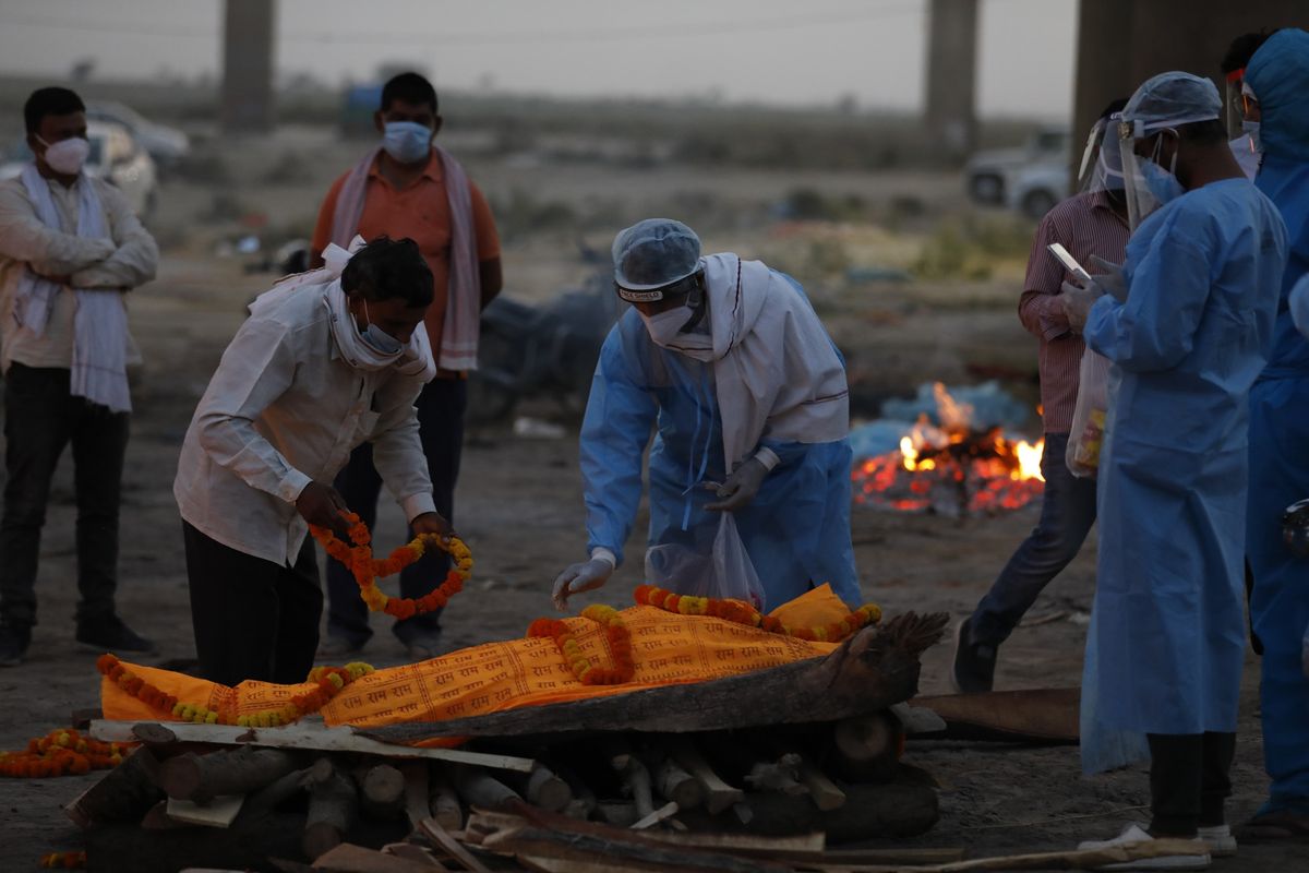 Anggota keluarga meletakkan bunga di atas jenazah Rajendra Prasad Mishra (62) yang meninggal karena Covid-19 sebelum dikremasi di Sungai Gangga, Prayagraj, India, 8 Mei 2021.