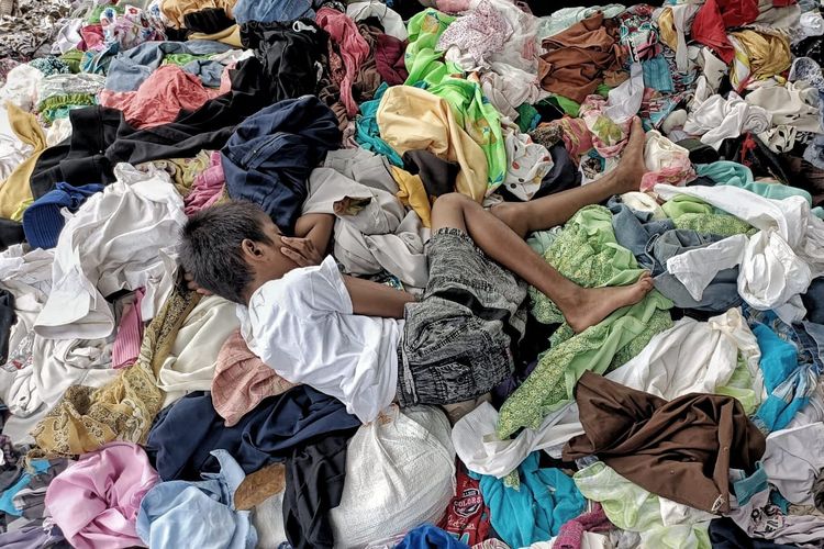 Seorang anak tertidur di atas tumpukan baju warga yang berhasil di evakuasi saat musibah kebakaran di Pasar Gembrong, Jakarta Timur pada (24/4/2022) lalu. Diketahui dari musibah tersebut, setidaknya total 400 rumah dan kios habis dilalapi api.  