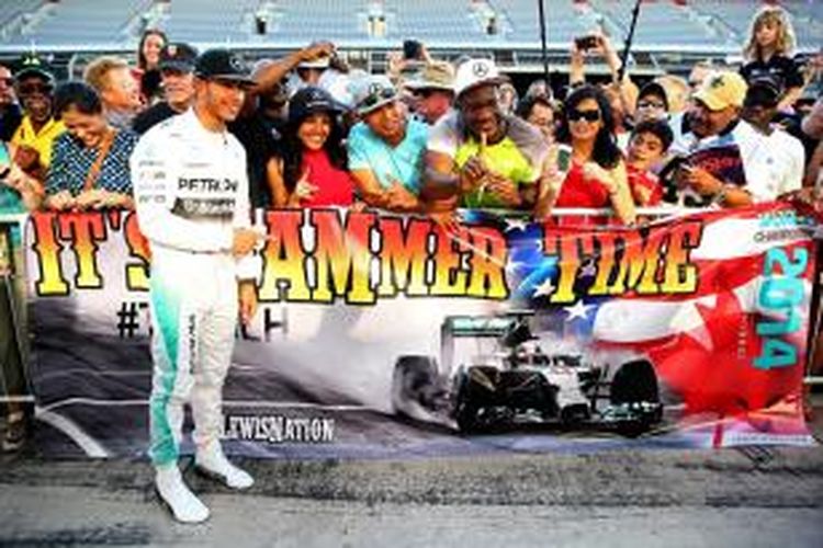 Pebalap Mercedes asal Inggris, Lewis Hamilton, berpose dengan para penggemarnya di pit lane Sirkuit Americas, Kamis (30/10/2014), jelang GP AS.