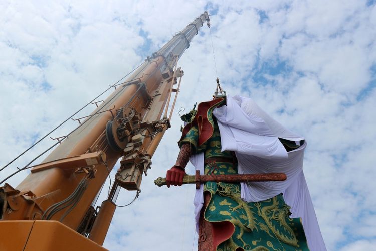 Petugas Badan Penanggulangan Bencana Daerah (BPBD) Pemkab Tuban, Jawa Timur, dengan menggunakan  alat berat crane menutup patung Dewa Perang Kongco Kwan Sing Tee Koen  dengan kain putih di Kelenteng Kwan Swie Bio, Minggu (6/8/2017). Patung setinggi 30,4 meter itu ditutup dengan kain oleh pengurus kelenteng karena adanya penolakan dari sejumlah elemen masyarakat atas patung itu. 