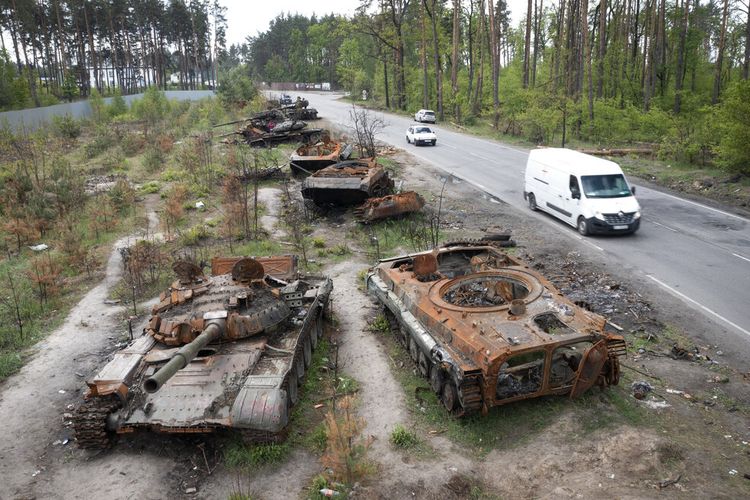 FILE - Mobil-mobil melewati tank-tank Rusia yang hancur dalam pertempuran baru-baru ini melawan Ukraina di desa Dmytrivka, dekat Kyiv, Ukraina, 23 Mei 2022. 