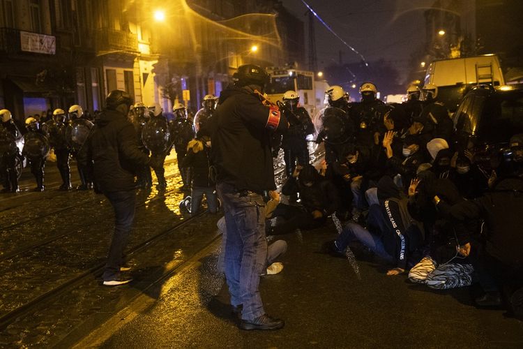 Seorang polisi berpakaian preman mengarahkan senjata peluru karet ke arah para perusuh di ibu kota Belgia, Brussel, Rabu (13/1/2021). Massa menuntut kebenaran karena kematian pria kulit hitam  yang ditahan oleh polisi pekan lalu di Brussel. Awalnya, aksi demonstrasi berjalan lancar, namun berakhir ricuh.