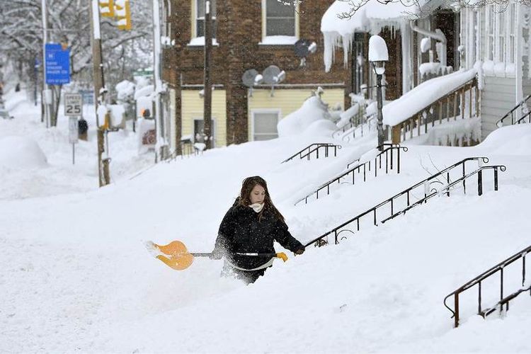 Seorang warga kota Erie, Pennsylvania menyingkirkan tumpukan salju dari depan pintu rumahnya.