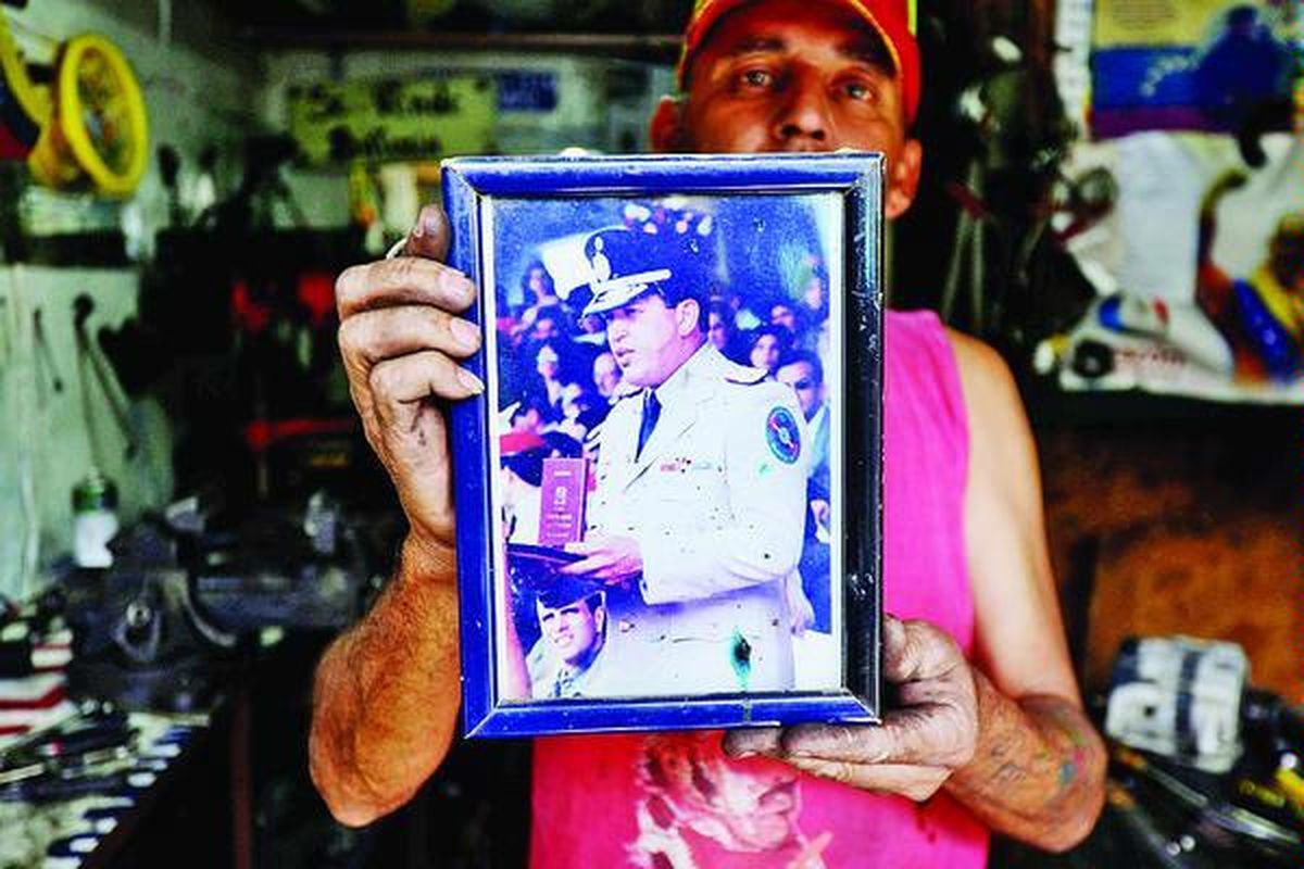 Seorang mekanik menunjukkan foto Presiden Venezuela Hugo Chavez di bengkelnya di Caracas, Venezuela, Rabu (2/1). Oposisi Venezuela meminta pemerintah mengungkapkan kondisi kesehatan Chavez setelah menjalani operasi kanker di Kuba tiga pekan lalu. 