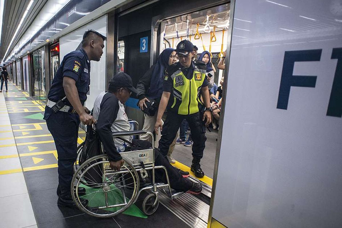 Petugas membantu seorang penyandang disabilitas naik ke kereta MRT di Stasiun MRT Bundaran HI, Jakarta, Minggu (24/3/2019). Moda Raya Terpadu (MRT) Jakarta Fase 1 dengan rute Bundaran HI - Lebak Bulus resmi beroperasi sejak diresmikan oleh Presiden Jokowi, Minggu hari ini.