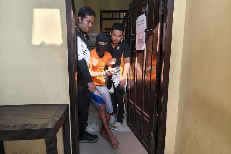 Pelaku saat dibawa dua anggota polisi di Mapolres Bangkalan. 
