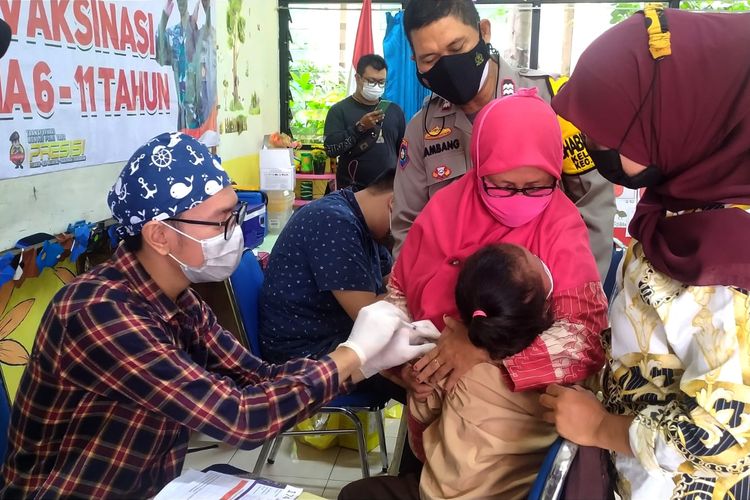 Tiga tenaga kesehatan muda dengan teliti dan bersemangat, menyuntikan satu dosis vaksin Covid-19 kepada setiap siswa di SDN 11 Duri Kepa, Jakarta Barat, Rabu (29/12/2021) 