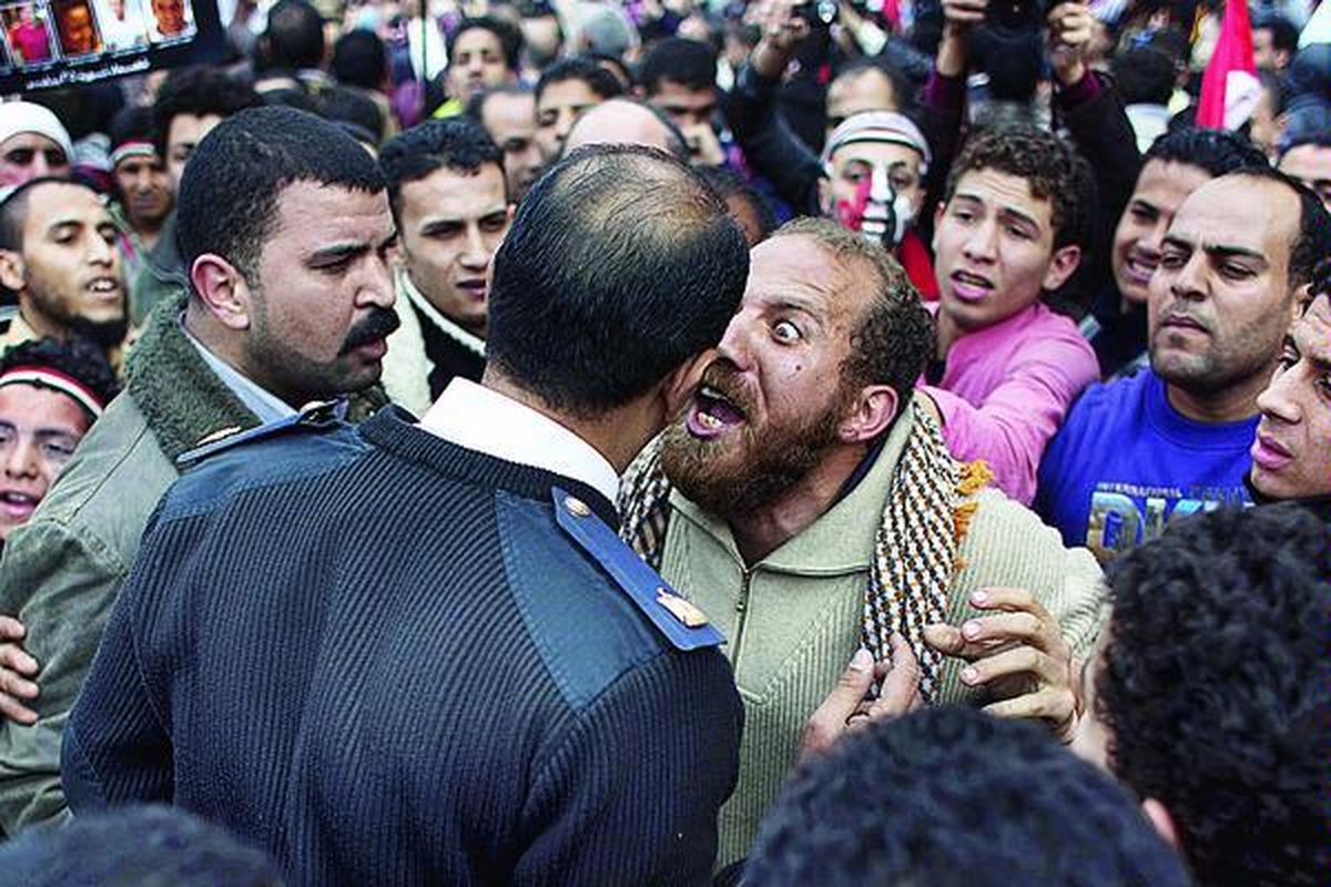 Seorang pengunjuk rasa Mesir berdebat dengan perwira polisi (tengah) yang sedang mengosongkan Alun-alun Tahrir di pusat kota Kairo, Mesir, Minggu (13/2). Militer mulai membongkar tenda-tenda yang didirikan pengunjuk rasa agar lalu lintas dan kehidupan sehari-hari di tempat itu normal kembali.