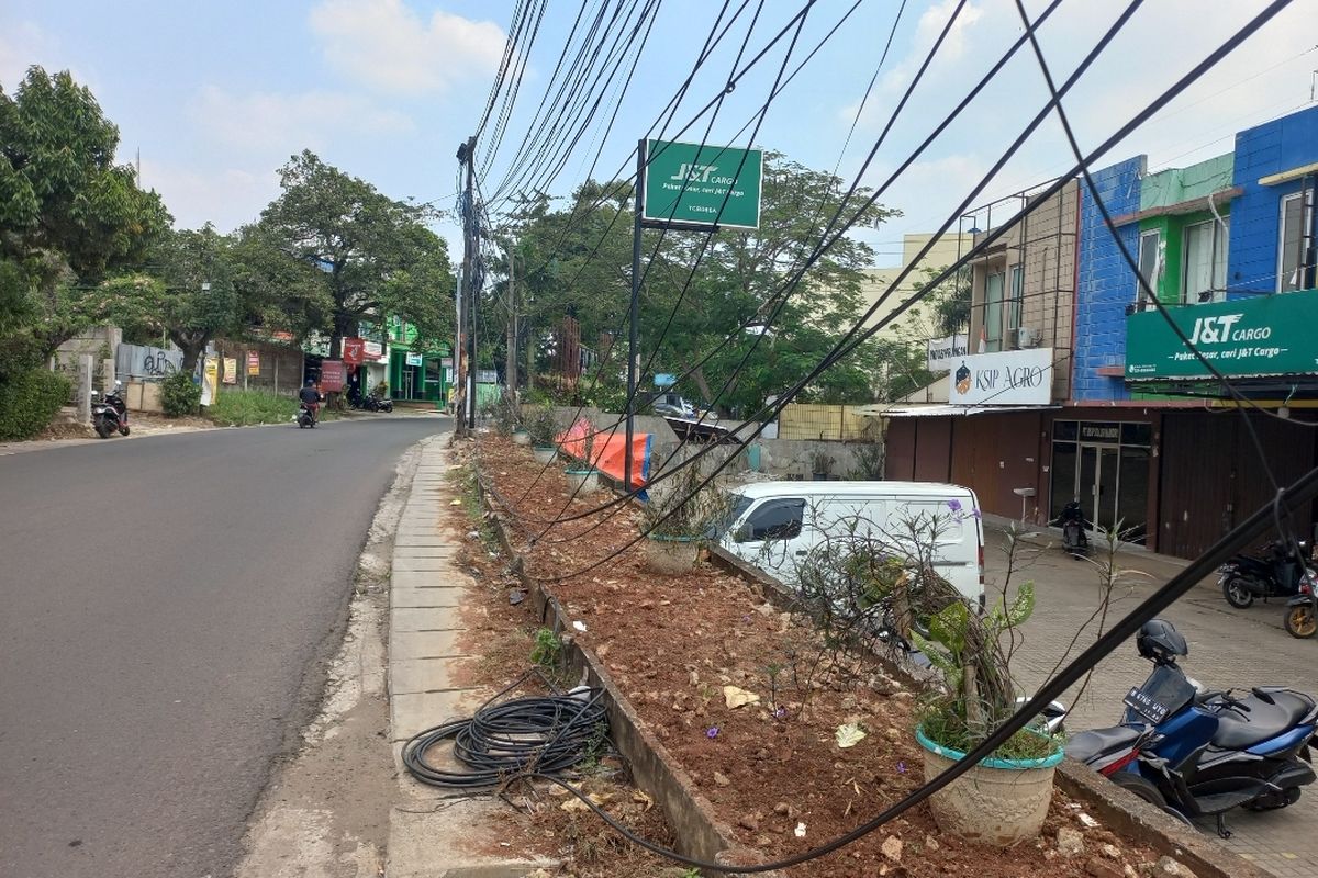 Penampakan kabel semrawut di depan JNT Cargo, Jalan Merpati Raya, Ciputat, Tangerang Selatan pada Senin (31/7/2023). Kabel-kabel itu terlihat ada yang menjuntai bahkan ada juga gulungan kabel yang berserakan di tanah.