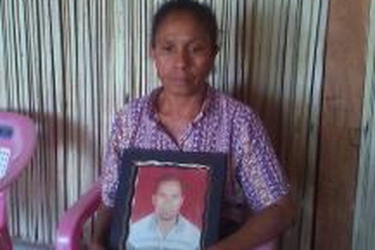 Josephine Binsasi memegang foto almarhum Paulus Usnaat yang tewas dibunuh di dalam sel tahanan Polsek Miomafo Timur dengan leher digorok dan alat kelamin dipotong. 
