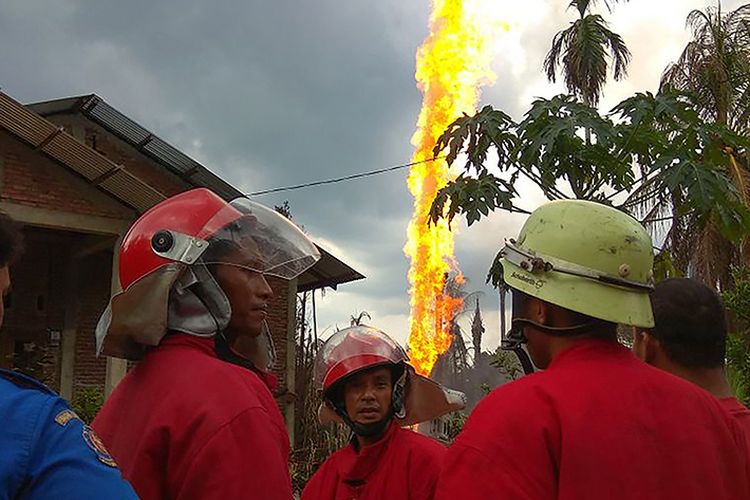 Petugas pemadam kebakaran berada di dekat lokasi kebakaran sumur minyak di Desa Pasi Putih, Kecamatan Ranto Peureulak, Kabupaten Aceh Timur, Rabu (25/4/2018). Sedikitnya 10 orang tewas dan belasan lainnya terluka akibat insiden meledaknya sumur minyak yang terjadi sekitar pukul 01.30 tersebut. .