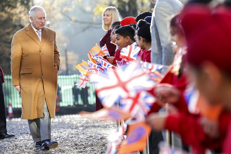 Raja Inggris Charles III tersenyum ketika berbicara dengan anak-anak sekolah setempat yang mengibarkan bendera saat berkunjung ke Guru Nanak Gurdwara yang baru dibangun, di Luton, Inggris, Selasa, 6 Desember 2022.