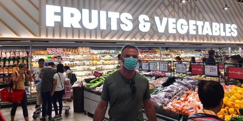 Melonjaknya kasus impor virus corona di Singapura menyebabkan meningkatnya jumlah warga yang kembali memakai masker. Salah satunya adalah seorang pria bule yang sedang berbelanja buah-buahan di supermarket FairPrice Xtra di pusat perbelanjaan VivoCity, kawasan Harbourfront, Sabtu siang (21/03/2020)