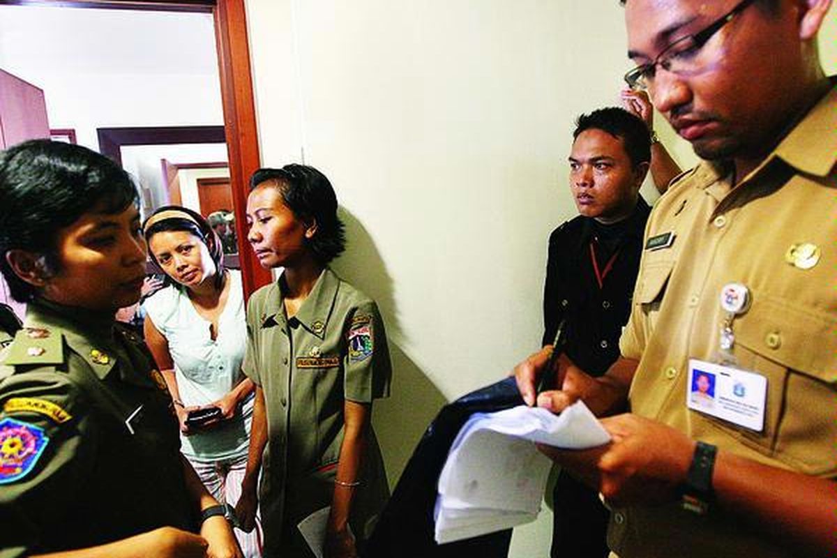 Petugas Kecamatan Tanah Abang menulis surat tanda terima penyerahan kartu identitas dari warga saat operasi yustisi kependudukan di Apartemen Sudirman Park, Jakarta Pusat, Kamis (30/9). Operasi itu bertujuan menekan angka pendatang ilegal di Jakarta.