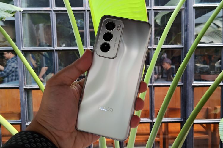 Bagian belakang Oppo Reno 12 kini dihiasi dengan motif mewah mirip air ombak yang bergelombang.

Kebetulan varian warna Oppo Reno 12 yang kami pegang adalah warna perak alias silver. Dengan warna ini, efek gelombang yang berwarna perak akan sedikit berubah warna menjadi hitam kemudian putih apabila punggung perangkat dilihat dari sisi berbeda.