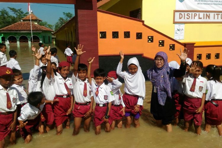 Anak-anak sebuah sekolah dasar di Dusun Bugel, Desa Panikel, Kecamatan Kampung, Cilacap, Jawa Tengah belajar ditengah kepungan banjir yang terjadi Selasa (14/11/2017)