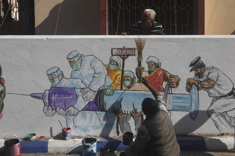 Seorang seniman memberikan sentuhan akhir pada mural yang menggambarkan pekerja garis depan membawa vaksin Covid-19 virus corona di Kolkata pada 2 Januari 2021.