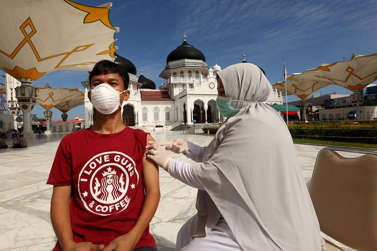 Warga mendapatkan suntikan vaksin COVID-19 oleh petugas kesehatan (kanan) pada vaksinasi merdeka di halaman masjid raya Baiturrahman, Banda Aceh, Aceh, Senin (6/9/2021). Vaksinasi merdeka yang digelar secara serentak pada 6-7 September 2021 di seluruh Indonesia merupakan program sinergi staf khusus Presiden bersama Kapolri dan  Panglima TNI untuk membantu pemerintah memutuskan mata rantai penyebaran serta penularan COVID-19. ANTARA FOTO / Irwansyah Putra/hp.