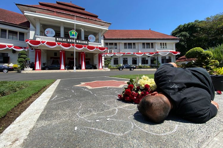 Seniman bernama Mukmin Ahmad (44) dari Malang Performance Art Community melakukan aksi teatrikal dengan menggambar jejak tubuhnya sendiri di halaman Balaikota Malang pada Kamis (10/8/2023), siang.