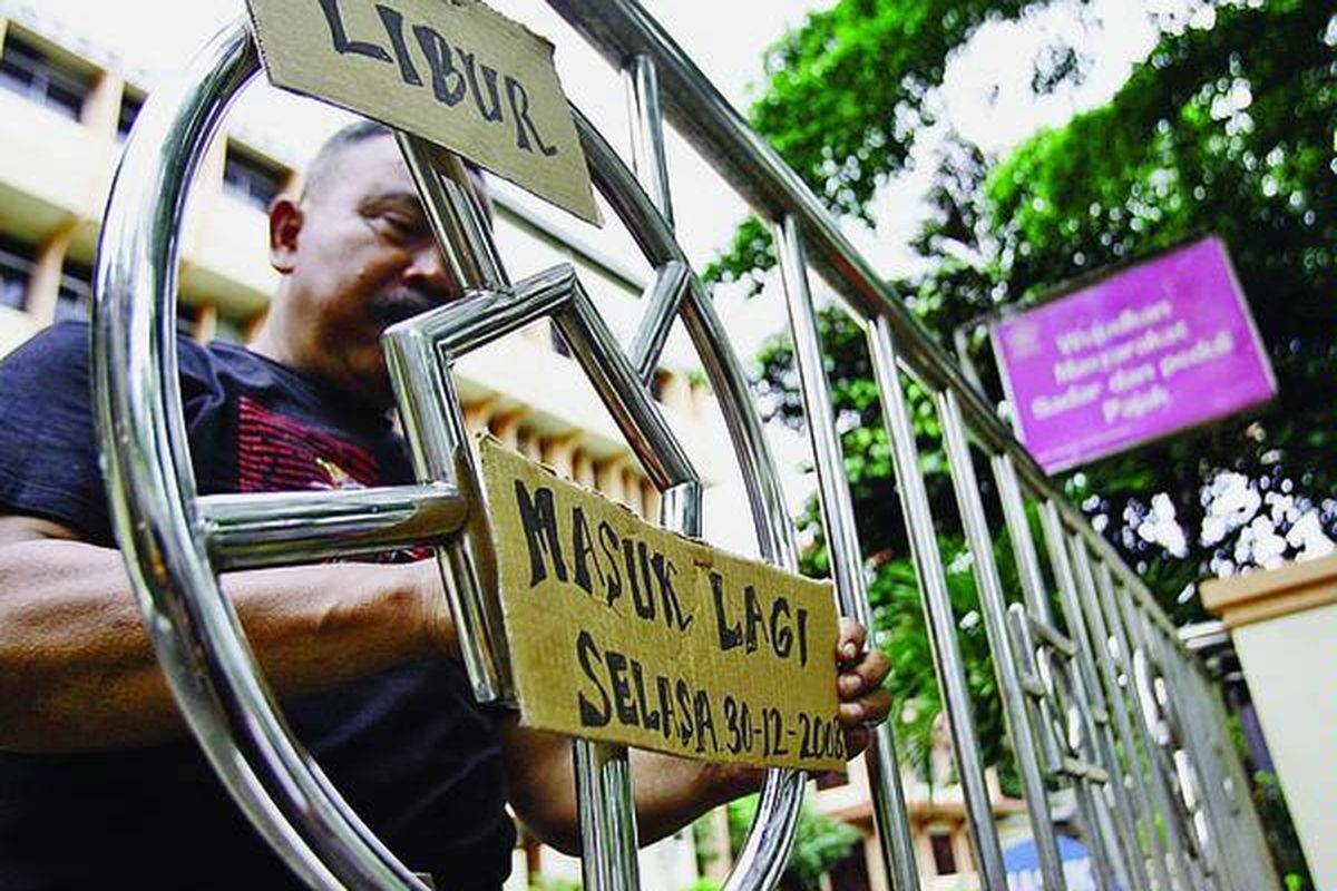 Petugas keamanan memasang papan informasi di depan gerbang Kantor Pratama Jakarta Pulogadung, Jumat (26/12). Petugas pajak yang seharusnya memberikan pelayanan kepada masyarakat lebih memilih mengikuti cuti bersama pegawai negeri sipil lainnya.  