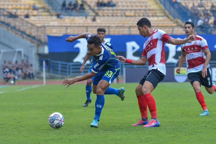 Winger Persib Erwin Ramdani berusaha melepaskan diri dari kawalan bek Madura United Reva Adi dalam duel Persib vs Madura United, yang dimenangkan Sape Kerrab dengan skor 3-1, Sabtu (30/7/2022) di Stadion Gelora Bandung Lautan Api (GBLA).